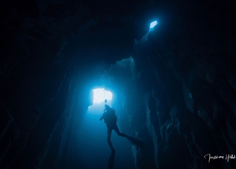 Un plongeur dans une grotte avec un trou au plafond