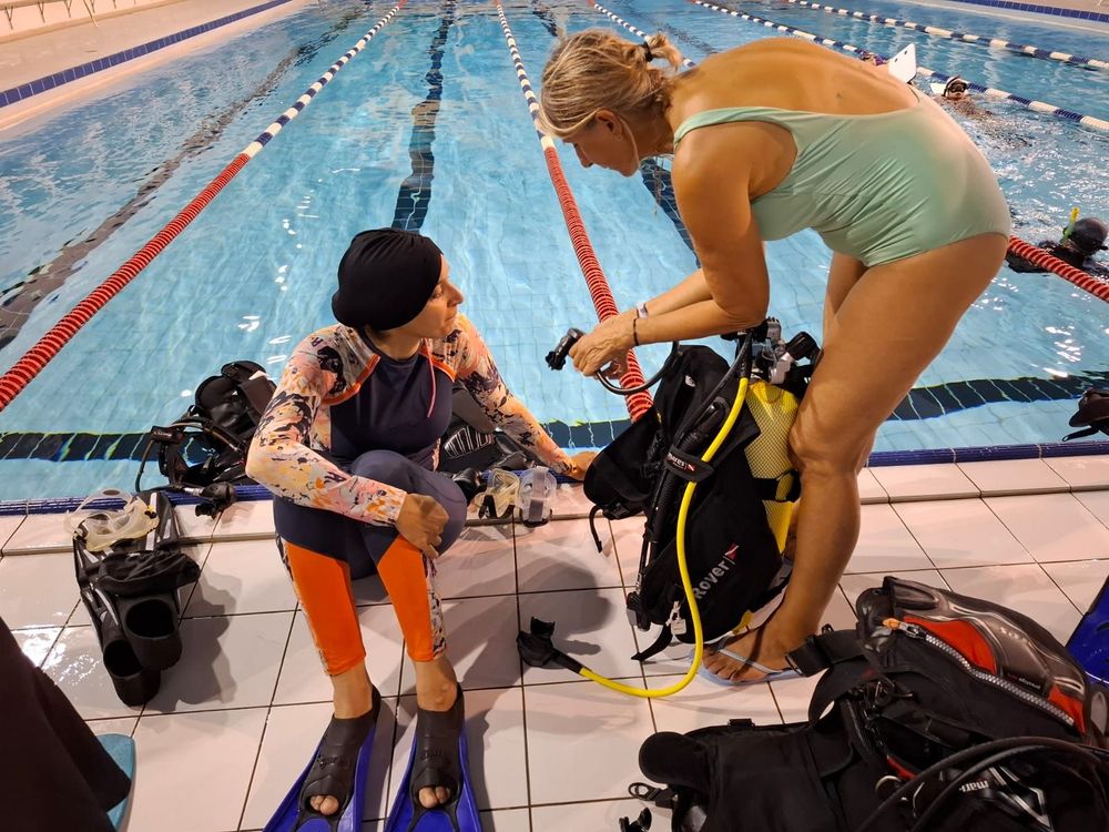 Deux plongeuses discutent sur le bord d'une piscine