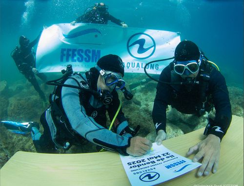 Deux plongeurs signent sosu l'eau un document.