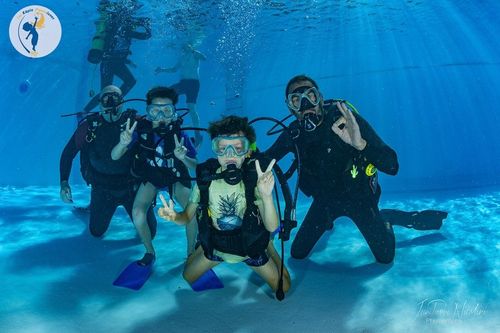 Des enfants avec leurs moniteurs dans une piscine.